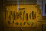 Softly lit display of bone tools and artifacts in a museum-like setting with glowing effects.