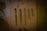 A set of five metal tools with a pointed end displayed vertically against a beige background. Each tool varies in length and design, with some featuring loops or rings at the top. There is a small numbered label '11' placed above the second tool from the left.