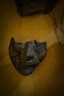 A close-up of an ancient cracked mask with faint claw marks and faded gold accents.