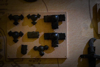 A collection of BDSM tools artfully arranged on a jet-black surface, hinting at disciplined indulgence.