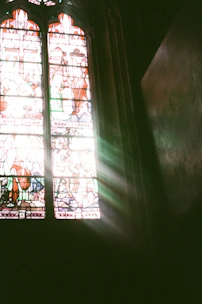 Close-up of a colorful stained glass window with intricate floral patterns illuminated by sunlight.