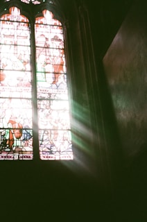 A symbolic composition featuring light rays breaking through stained glass motifs.