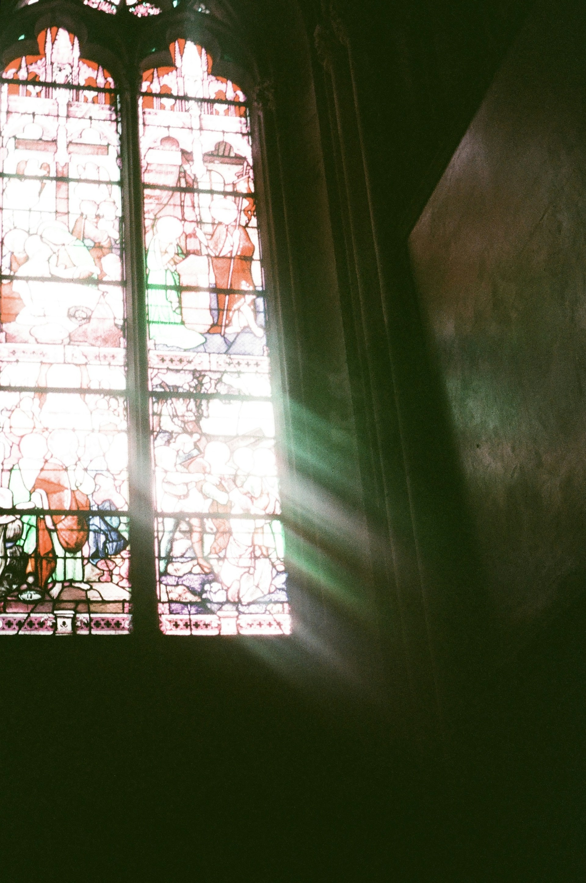 Sunlight filtering through stained glass windows, casting colorful patterns on a quiet reading space filled with diverse faith-related texts.