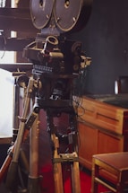 A cozy film studio office with vintage movie posters and a camera on a tripod.