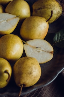 a plate of pears and a leaf on a table