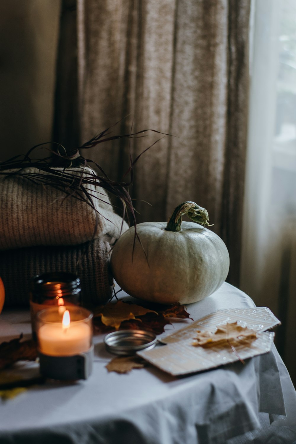 a table topped with candles and pumpkins next to a window
