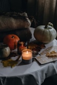 A warm autumn table set with pumpkins, candles, and rustic decor.