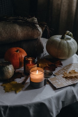 A warm autumn table set with pumpkins, candles, and rustic decor.