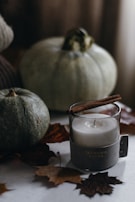 A collection of seasonal candles with autumn leaves and cinnamon sticks arranged around them.