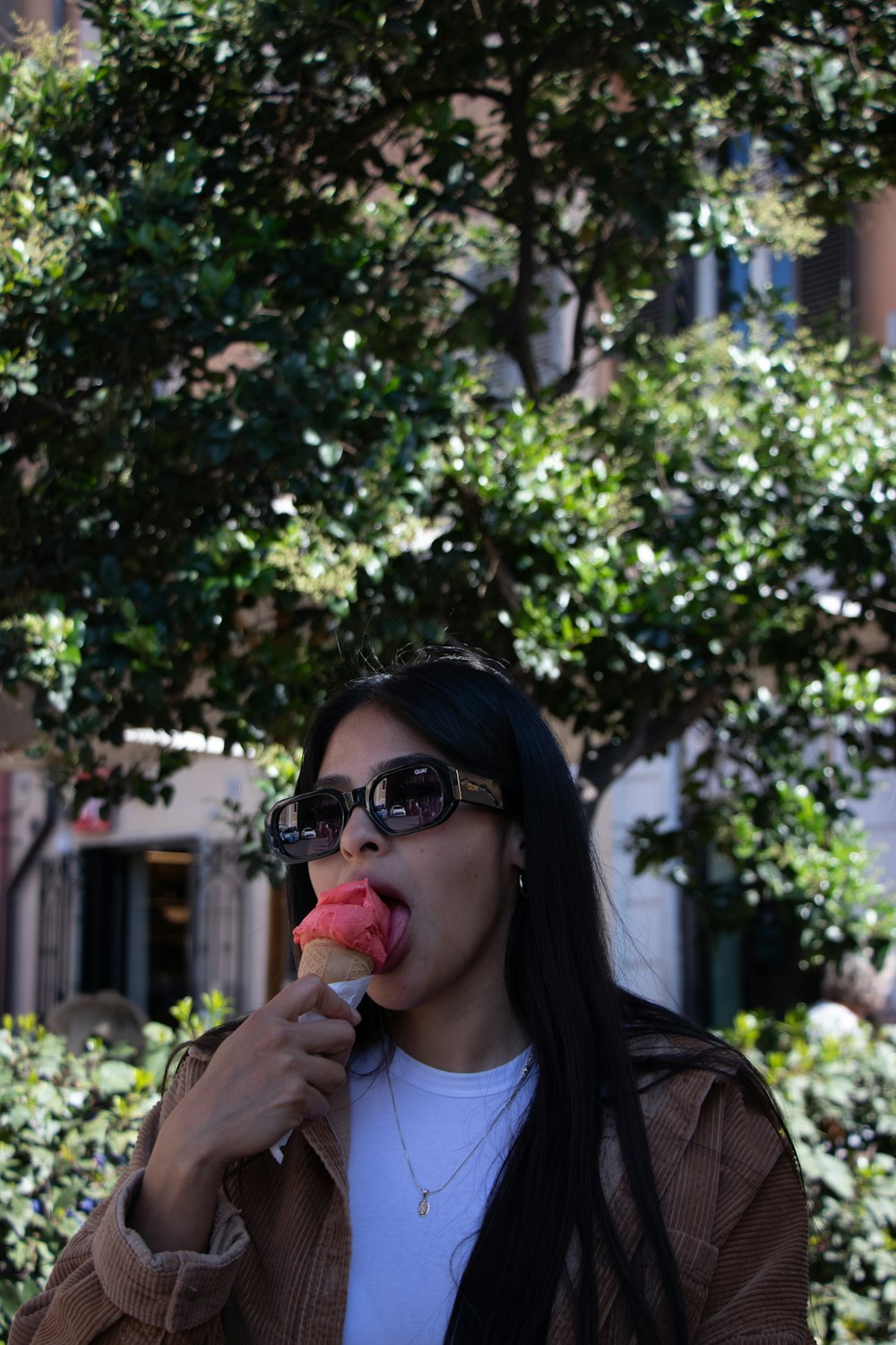 a woman eating a piece of food in front of a tree