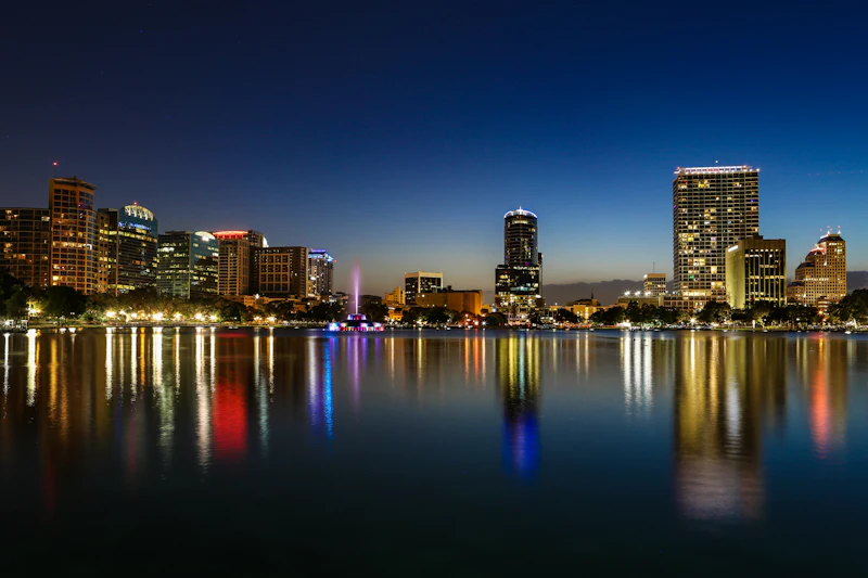 Prédios de Orlando iluminados à noite, refletidos no lago
