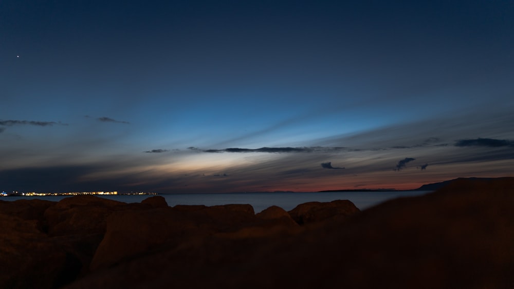 a view of the ocean at night from a rocky shore