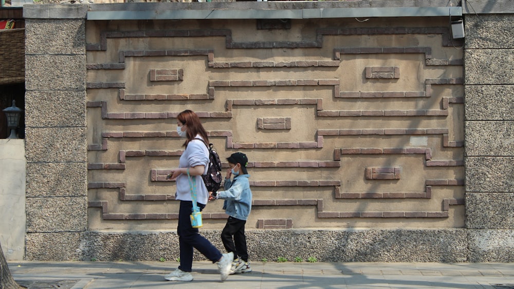 a woman and a child walking down a sidewalk