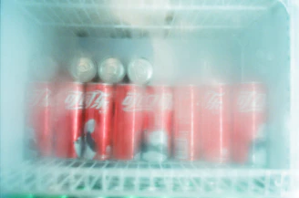 Close-up of frosty cans stacked with subtle smoke effects and glowing red neon accents.