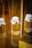 Several glass jars and a box containing dried herbs or plant materials are displayed on a glass shelf. The jars have handwritten labels in an old-fashioned script and are sealed with paper covers. The setting appears to be a museum display or an apothecary.