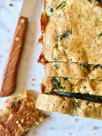 An overhead shot of a savory inclusion loaf sliced open to reveal olives and herbs inside.