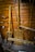 A variety of old wooden tools are displayed against a wooden wall. The tools include large paddles and wooden handles, possibly used for agricultural or manual tasks. The wood has a weathered look, indicating age and use.