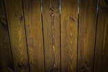 A close-up view of vertically arranged wooden planks with visible grain patterns and a dark brown stain.