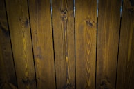 A close-up view of vertically arranged wooden planks with visible grain patterns and a dark brown stain.