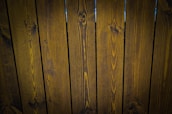 A close-up view of vertically arranged wooden planks with visible grain patterns and a dark brown stain.