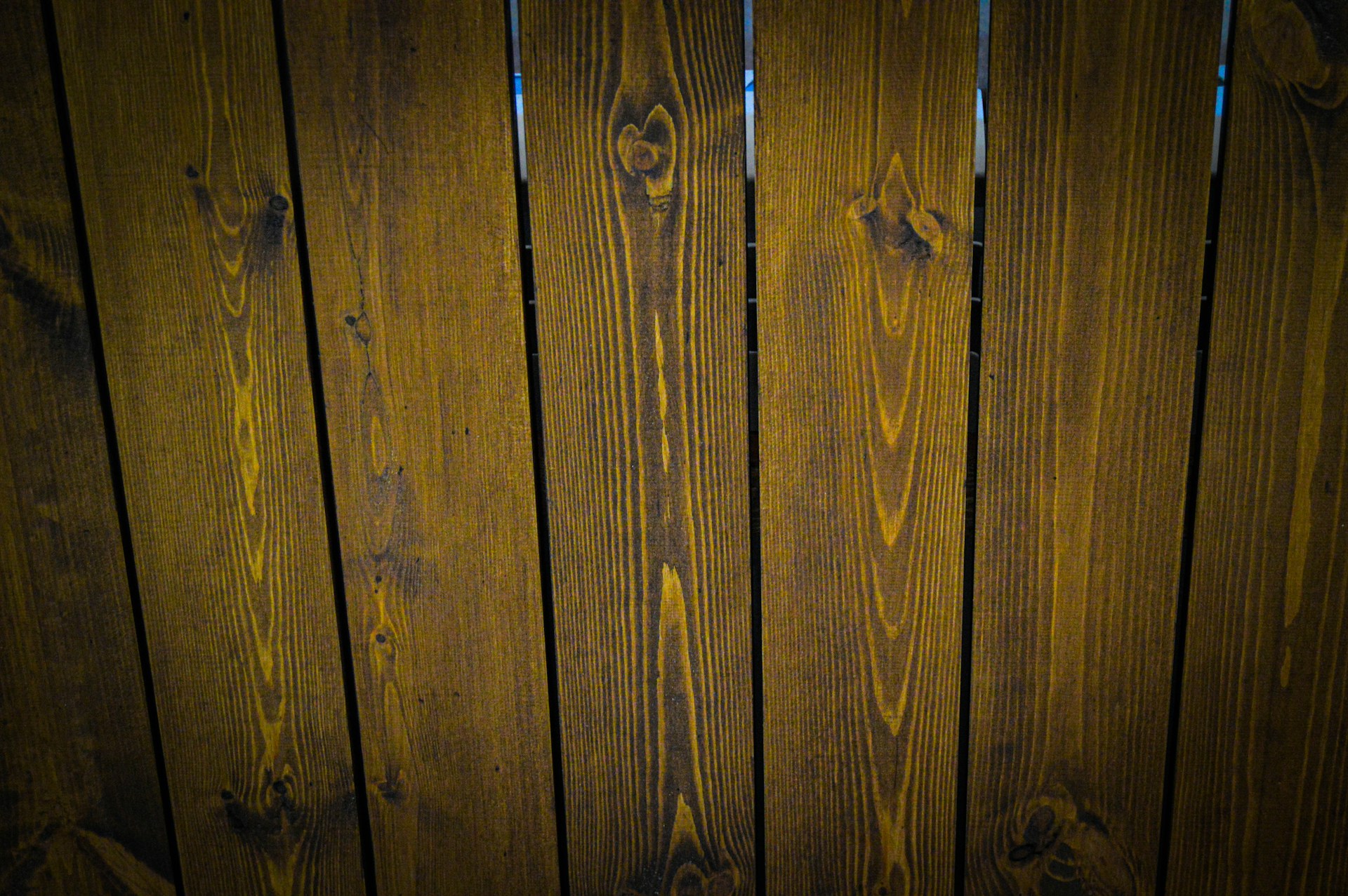 A close-up view of vertically arranged wooden planks with visible grain patterns and a dark brown stain.