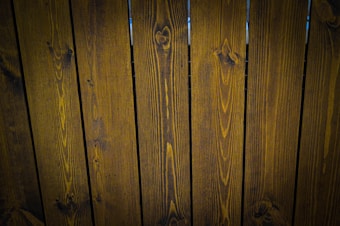 A close-up view of vertically arranged wooden planks with visible grain patterns and a dark brown stain.