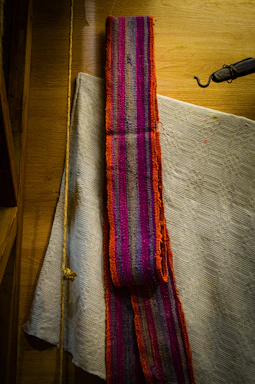 A colorful Andean textile border framing a rustic wooden table with a vintage microphone.