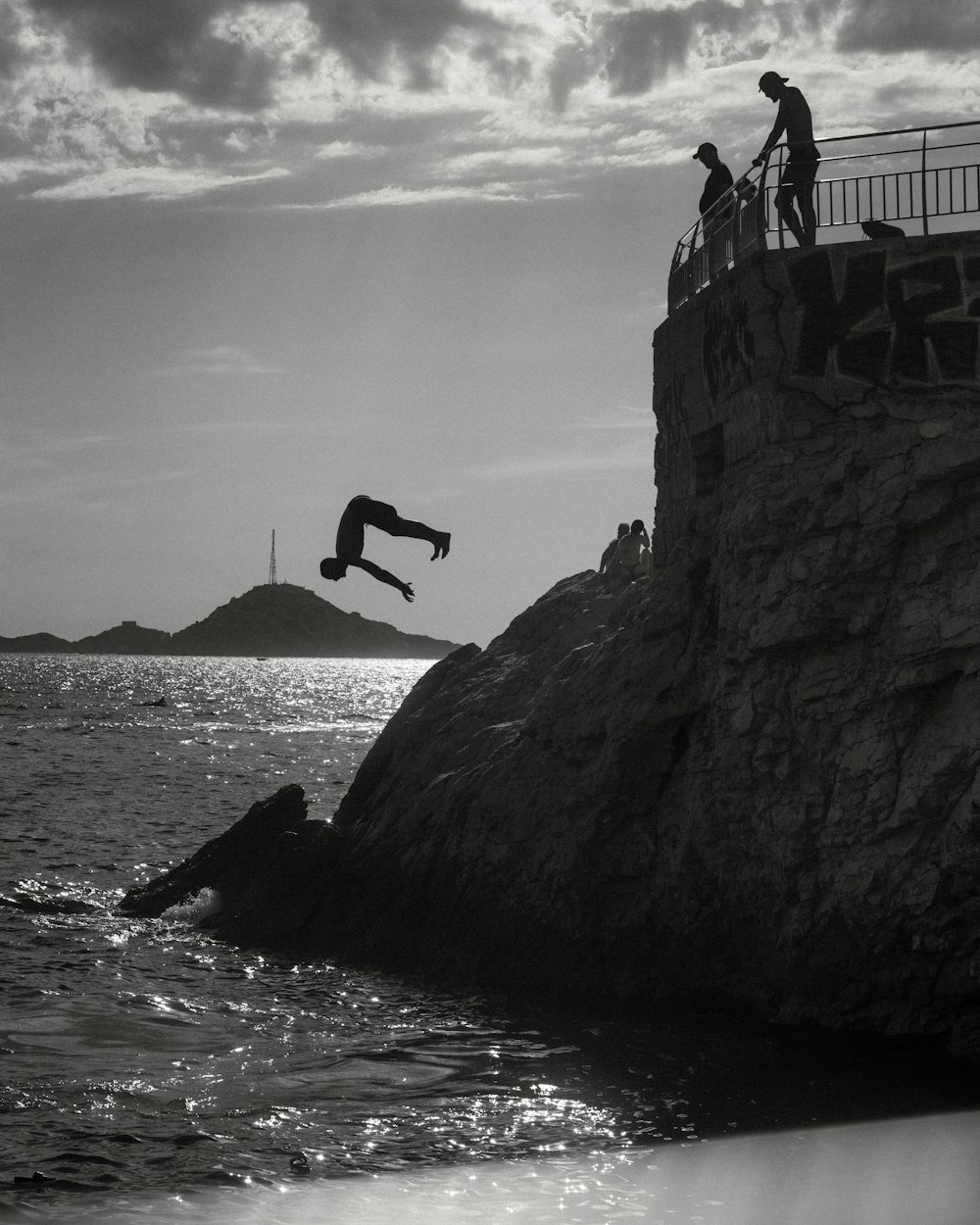 a man jumping off a cliff into the ocean