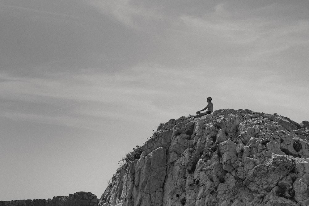 a man sitting on top of a large rock