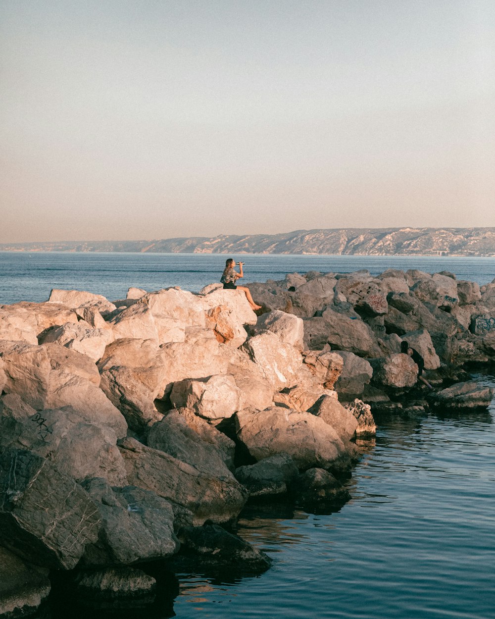 a person sitting on a rock by the water