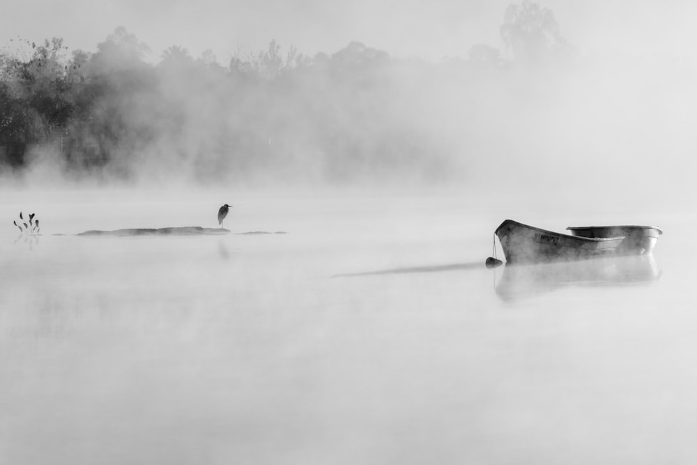 a boat floating on top of a lake covered in fog