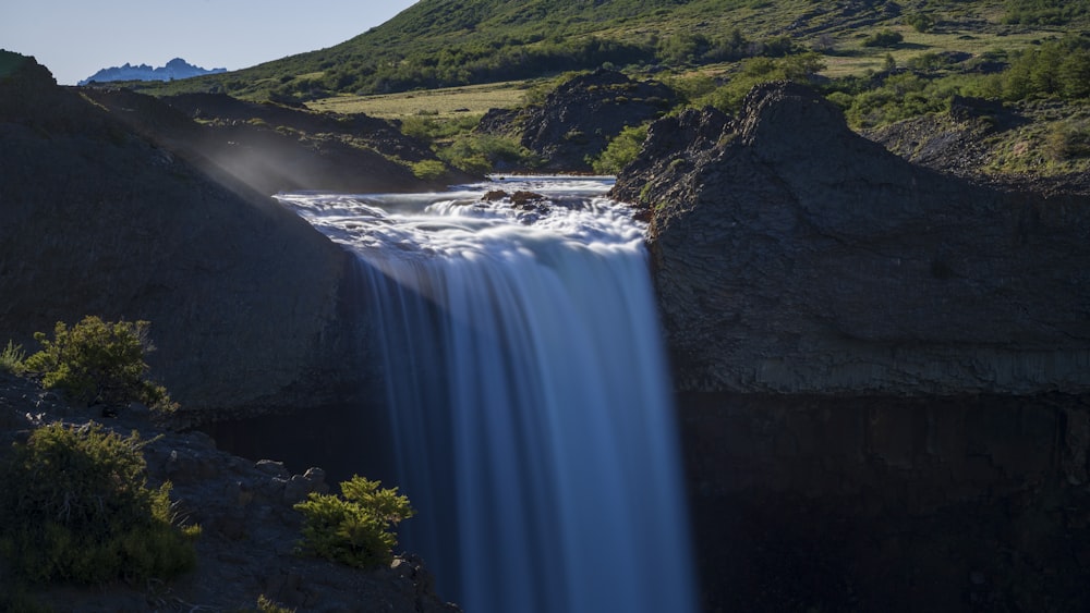 a large waterfall with a mountain in the background