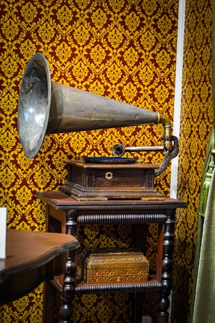 A classic gramophone with a large brass horn sitting next to vinyl records.
