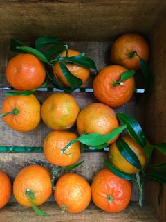 A rustic wooden crate filled with ripe oranges and lemons.