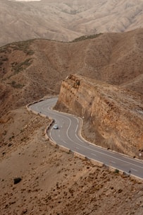A scenic Moroccan desert road with a comfortable tourist car driving through.