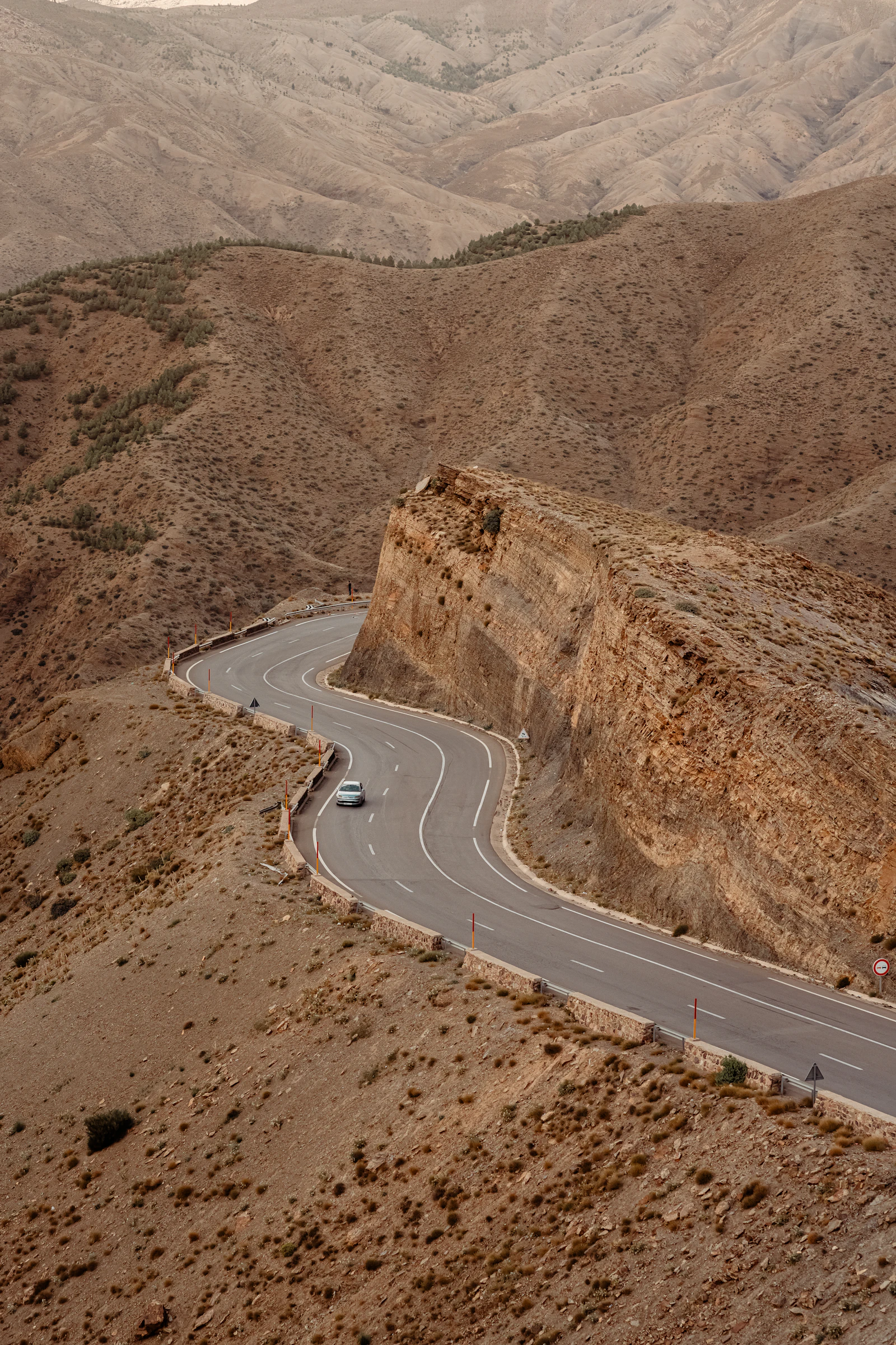 A paved road winding through pale Moroccan mountain rock