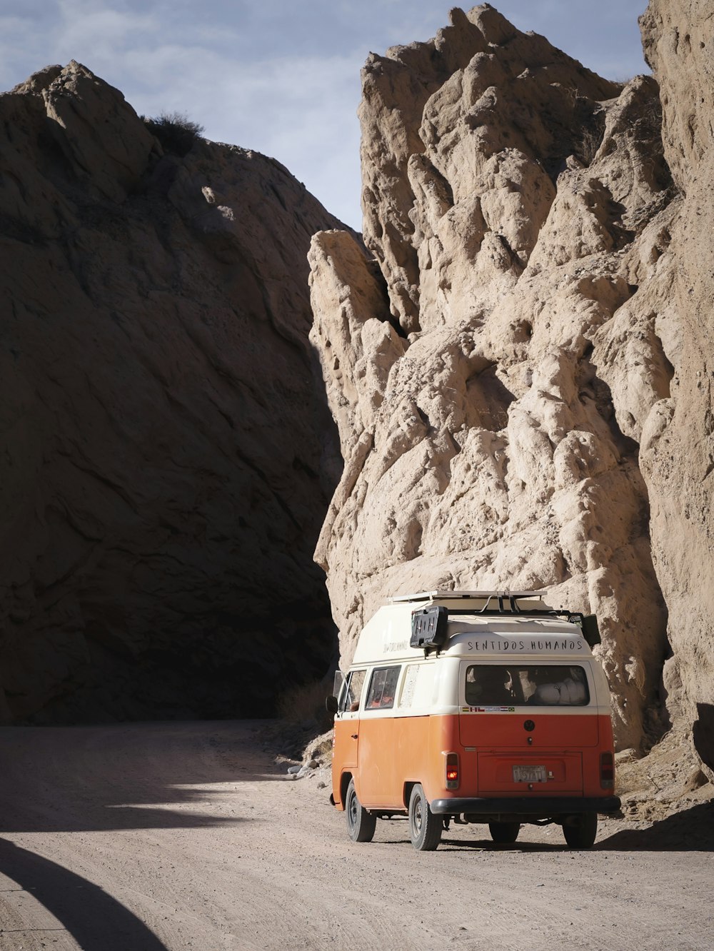 an orange and white van parked in front of a mountain