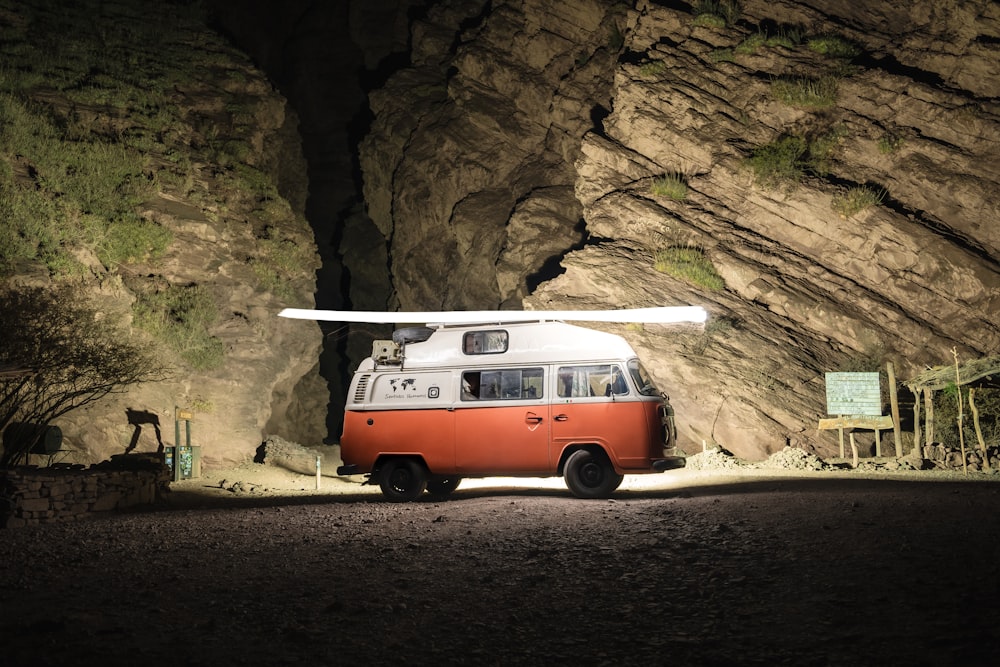 an orange and white van parked in front of a mountain