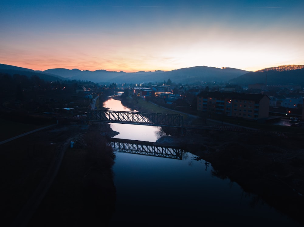 the sun is setting over a river and a bridge