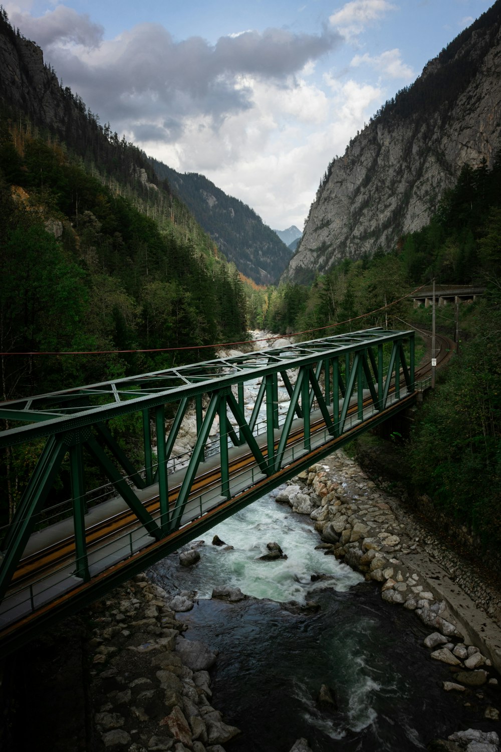 a bridge over a river with mountains in the background