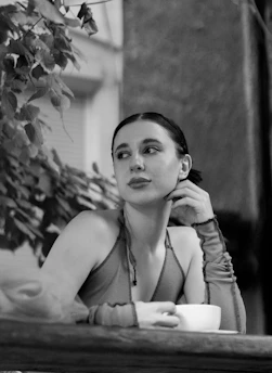 A serene figure sits beneath a tree, cups arranged thoughtfully around them, embodying contemplation and introspection.