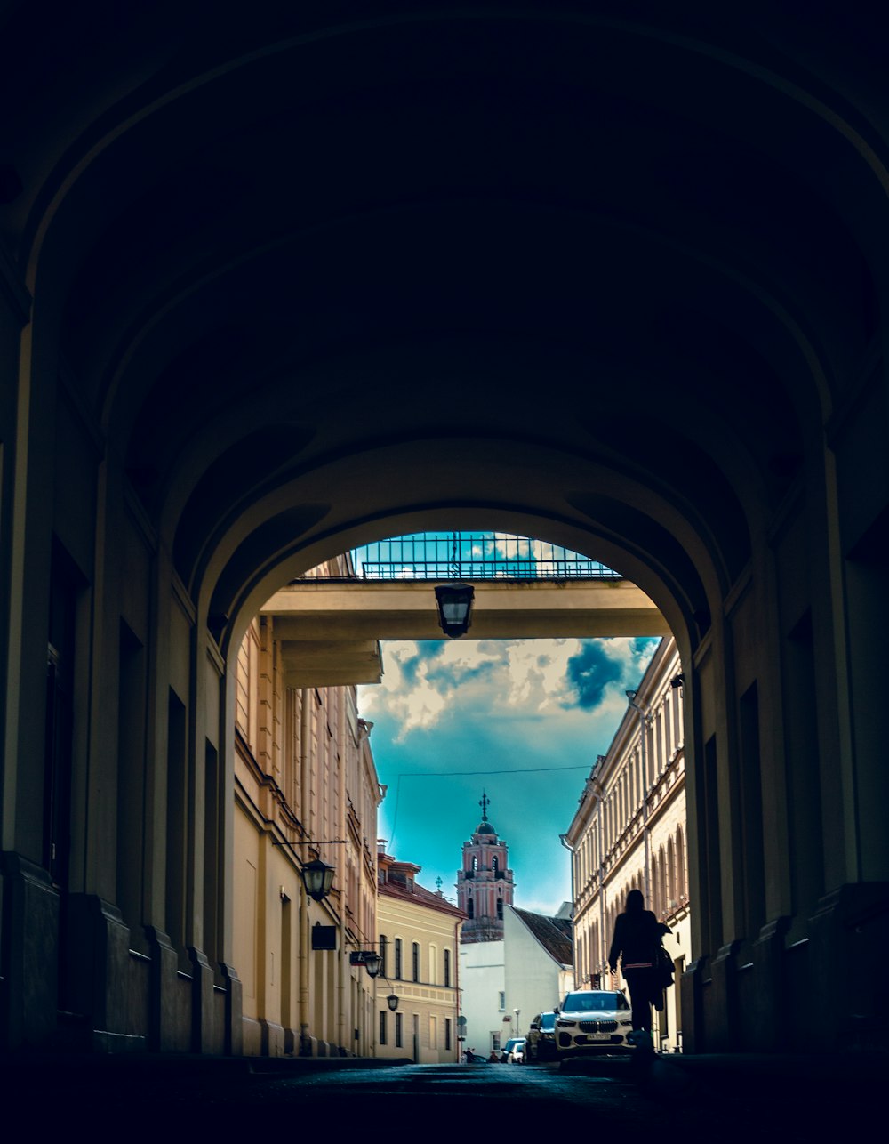 um homem caminhando por uma rua sob uma ponte