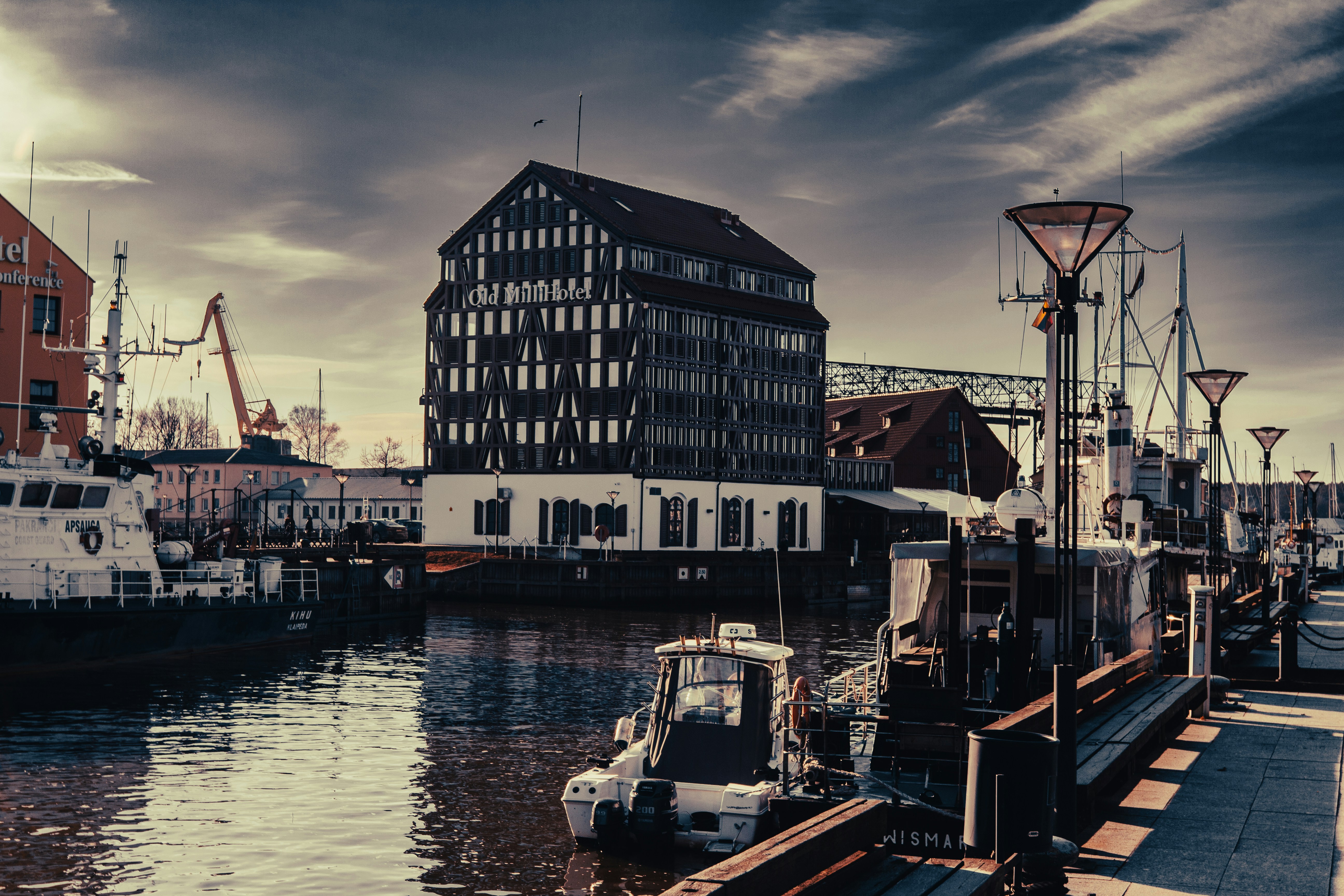 a boat docked in a harbor next to a tall building, 
