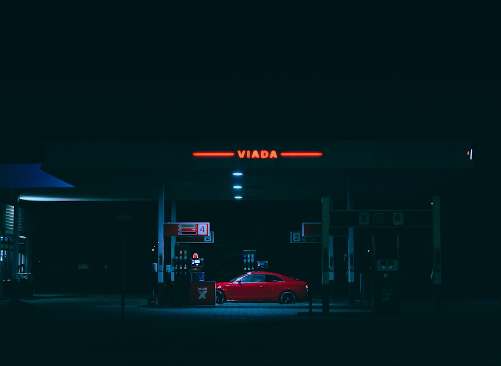 a red car is parked in front of a gas station