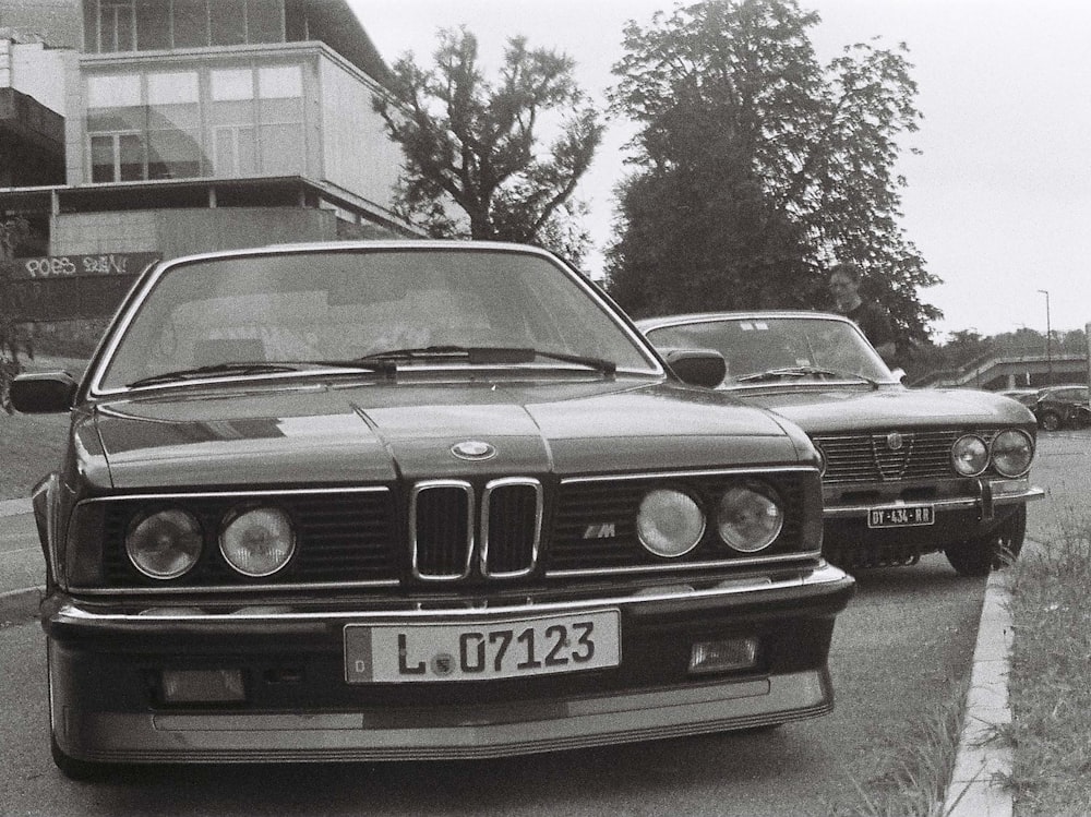 a black and white photo of two bmws