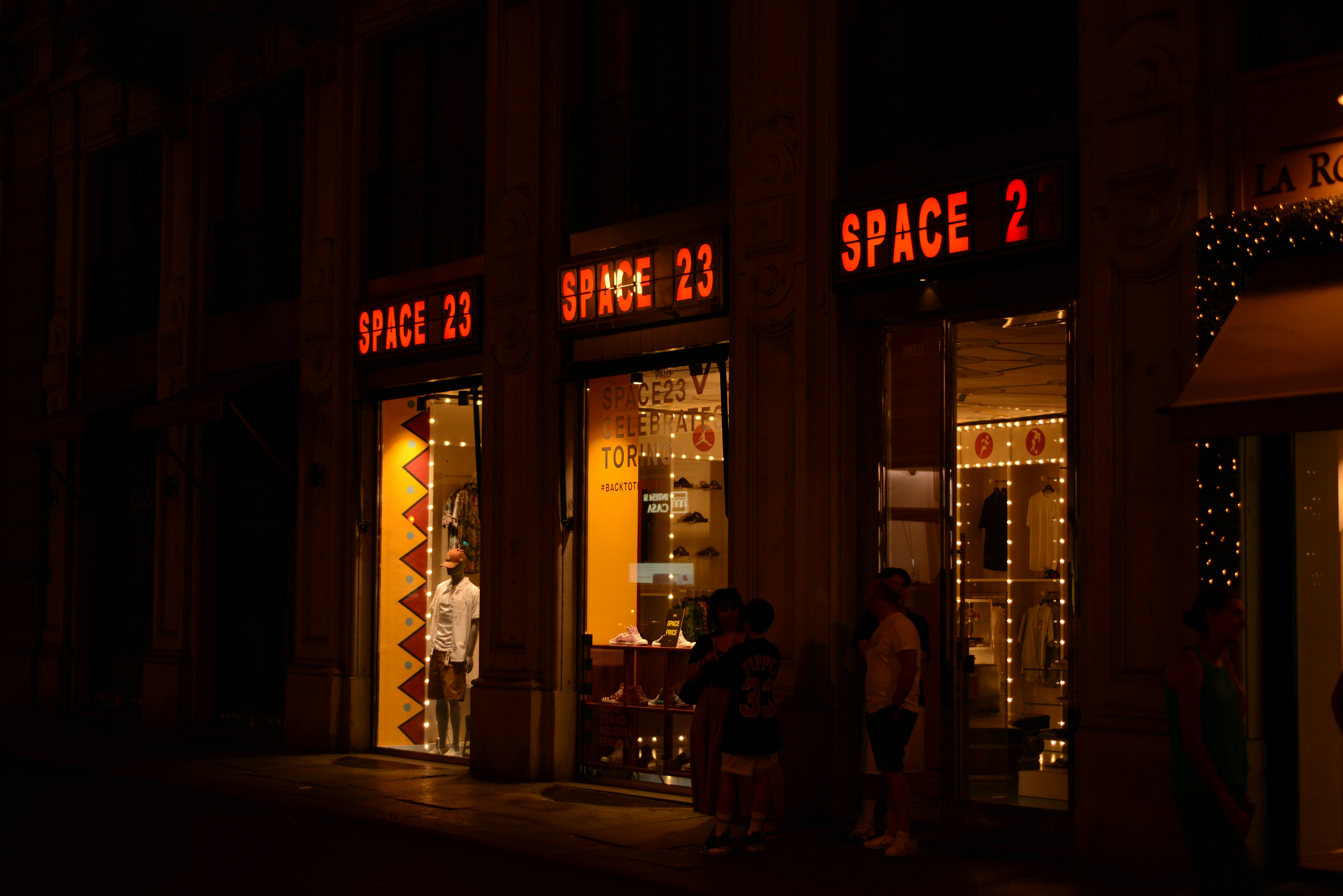 a group of people standing outside of a store at night