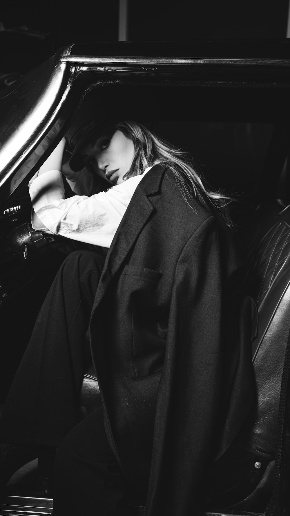 a black and white photo of a woman sitting in a car