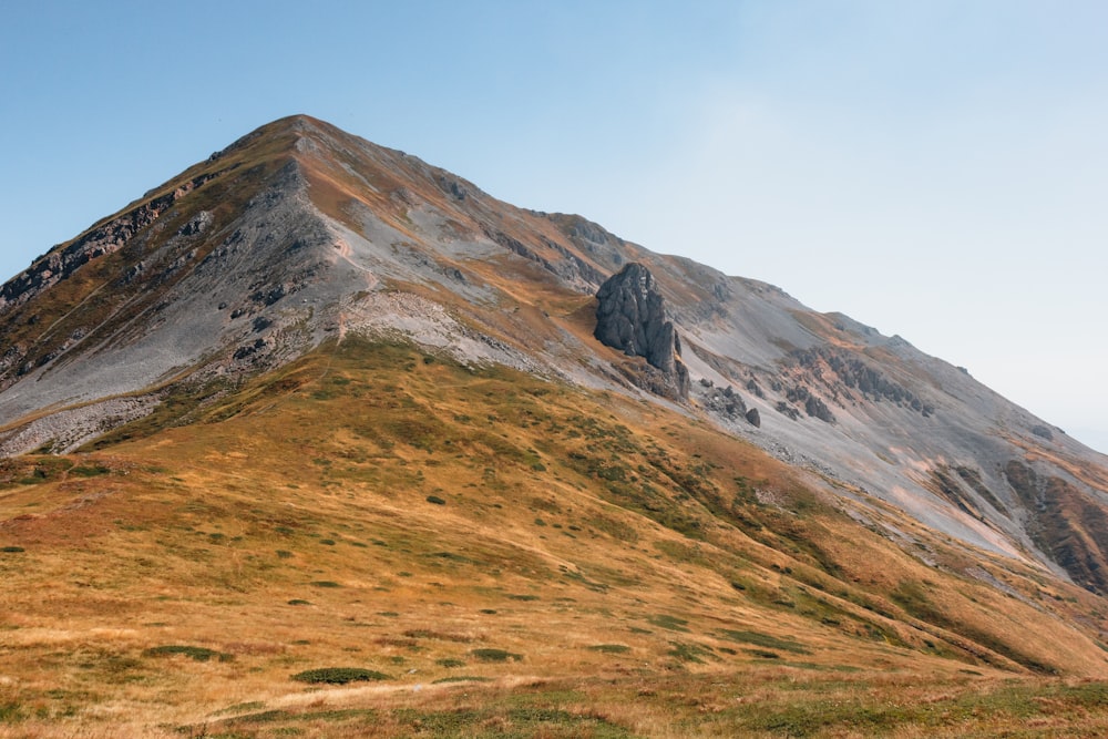 a very tall mountain covered in grass and dirt