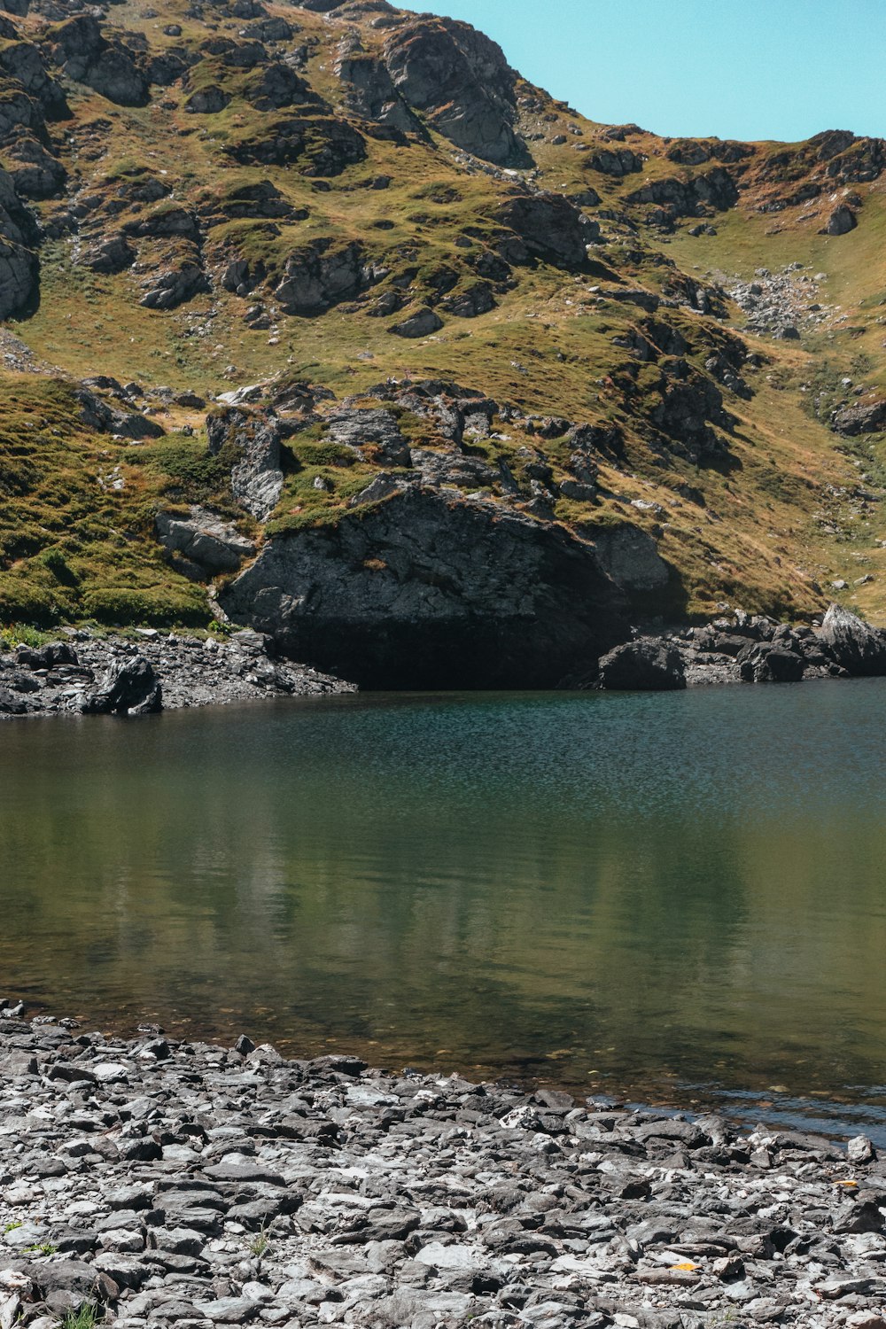 a man standing on a rocky shore next to a body of water