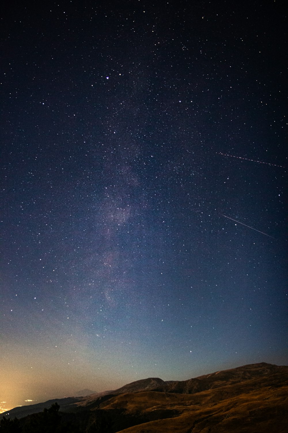 a view of the night sky from a hill